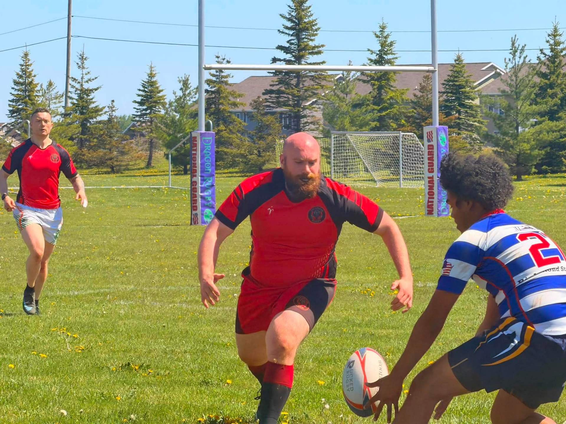 Berserkers player in red running toward a defender with the rugby posts behind, in Michigan's Upper Peninsula